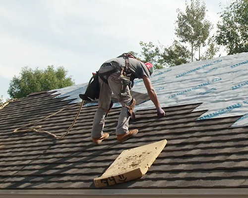 A roofer installs shingles on a roof.