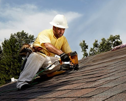 A roofing contractor installing shingles on a roof.
