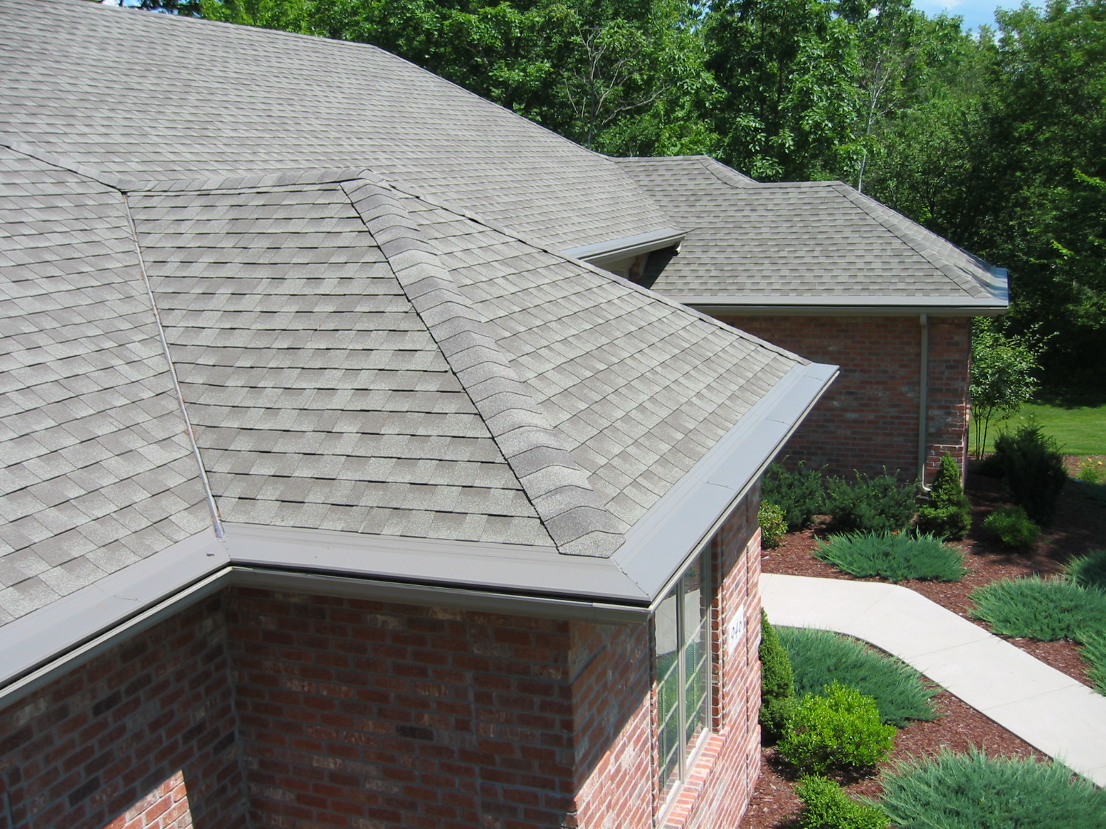 The edge of a home roof with gutters covered by Gutter Topper.