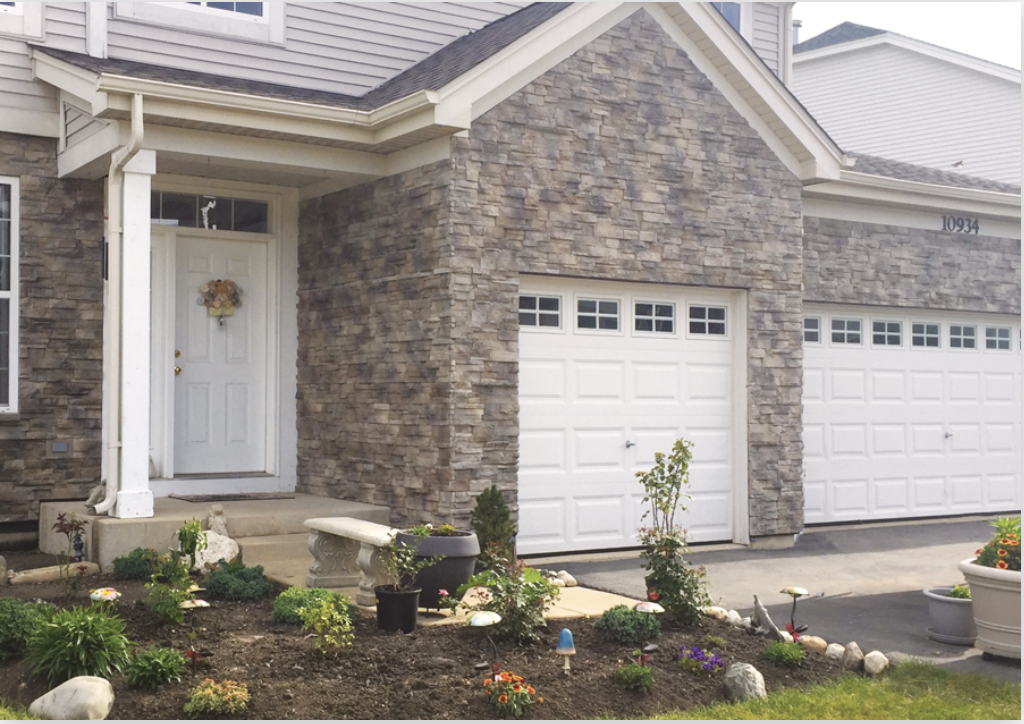 front of home finished in stone with white trim, door and garage doors