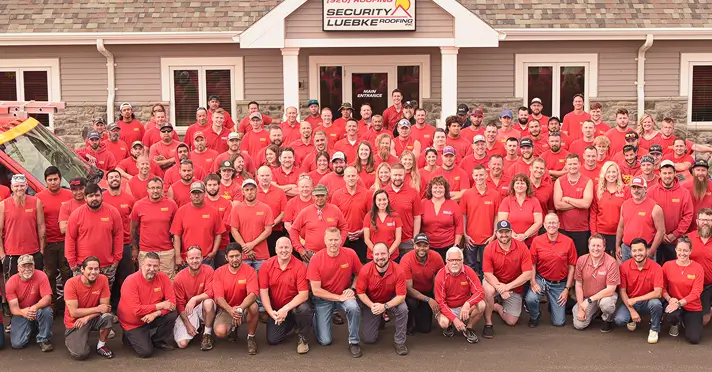 Group photo of entire SLR team, in their bright red uniform shirts, posing proudly in front of their office